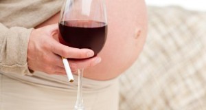 Schwangere Frau mit einem Glas Rotwein in der Hand