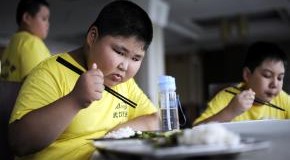 Übergewichtiger chinesischer Junge beim Mittagessen