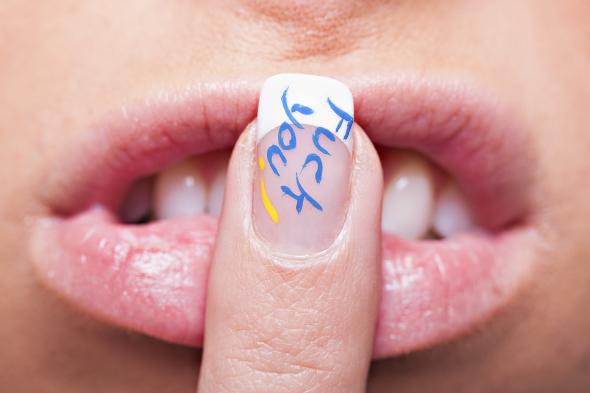 Eine Frau mit einem Finger auf den Lippen - auf dem Nagel steht "F*ck You"