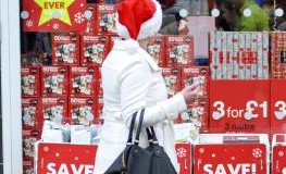 Frau mit Nikolausmütze läuft an einem Geschäft zur Weihnachtszeit vorbei