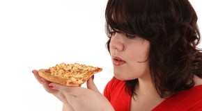 Heißhungerattacken: Die Frau isst ein Stück Pizza