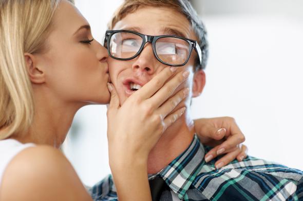 Frau küßt einen jungen Mann mit Brille auf die Wange.