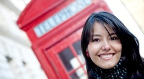 Junge Frau in London vor einer Telefonzelle