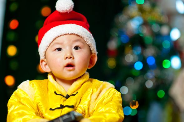 Kleiner Junge in traditioneller chinesischer Kleidung mit einer Weihnachtsmütze.