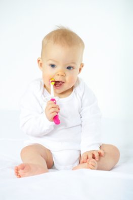 Zahnpflege beim Säugling - Baby putzt den Gaumen und Milchzähne mit einer Zahnbürste
